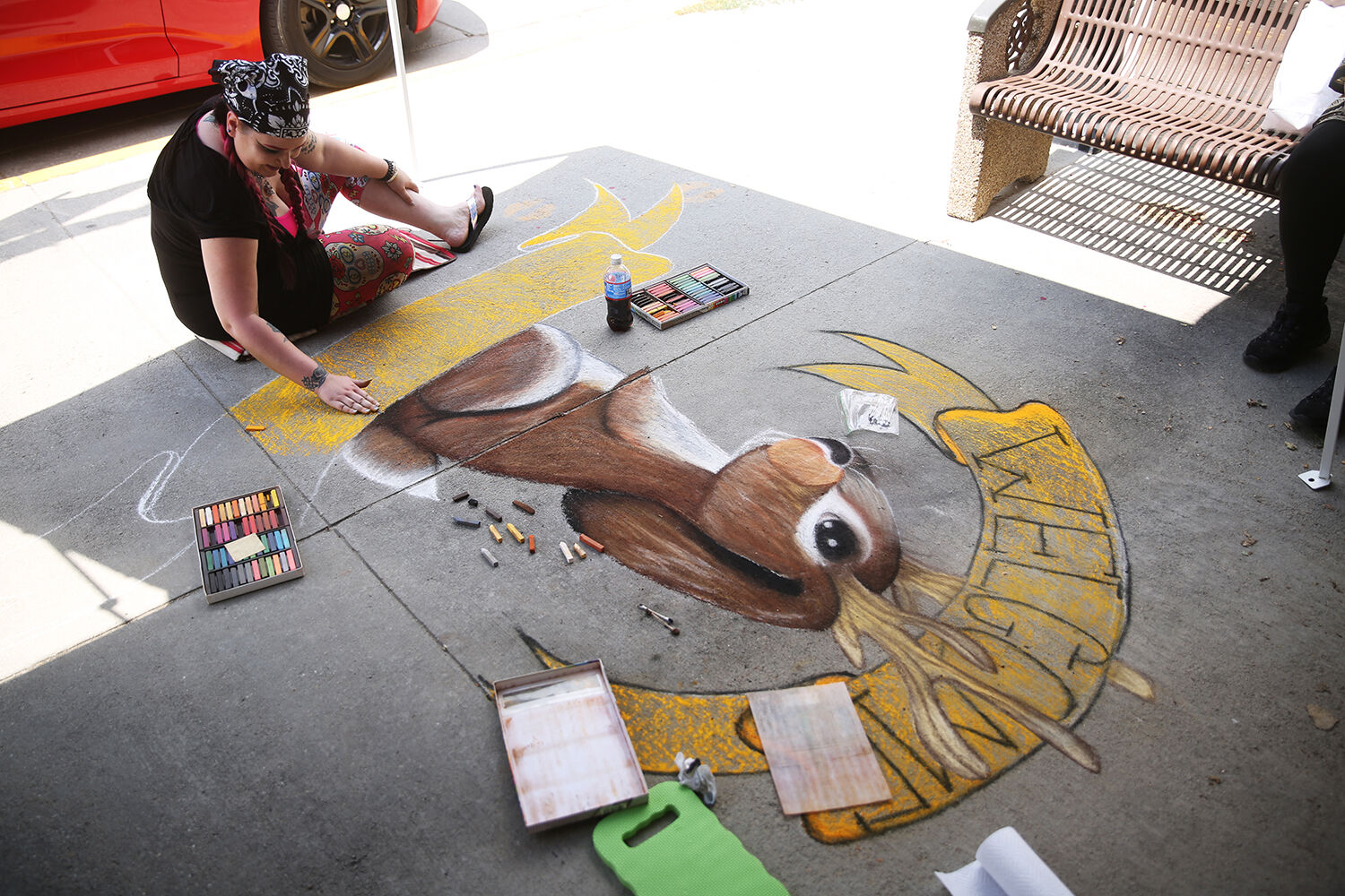 Laura Thorn uses her hand to spread out the yellow chalk